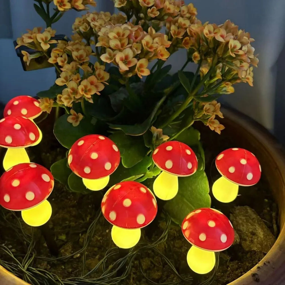 Solar mushroom garden light set nestled among leaves: red caps with warm yellow glow bulbs