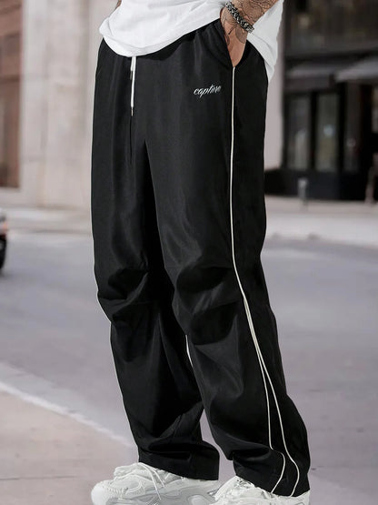 Men's wide-leg trousers in black with side stripe, drawstring waist, and white trim