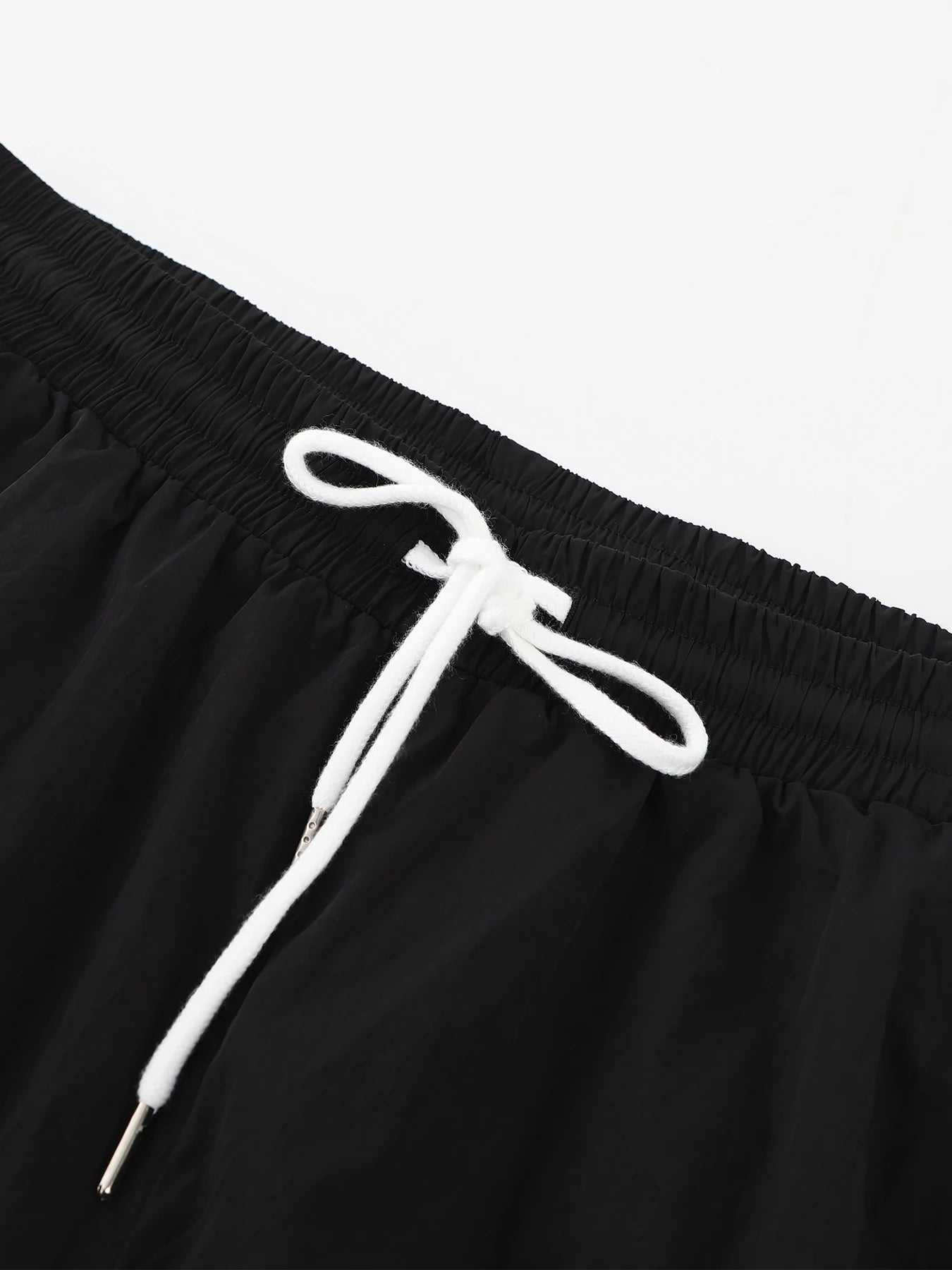 Black drawstring waist on wide-leg trousers with white cord and elastic waistband