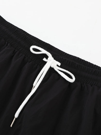 Black drawstring waist on wide-leg trousers with white cord and elastic waistband