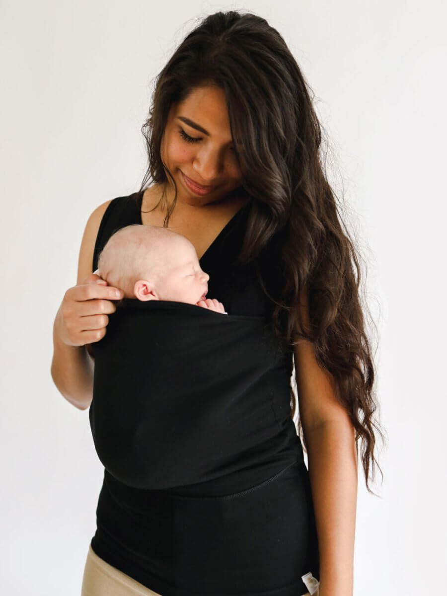 Black baby carrier sling T-shirt with sleeveless wrap panel, holding a newborn.