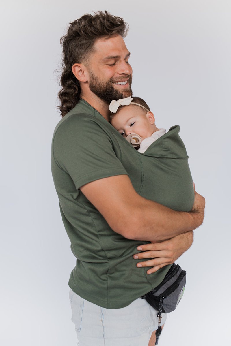 Olive green baby carrier sling T-shirt with short sleeves and wrap carrier, holding infant.