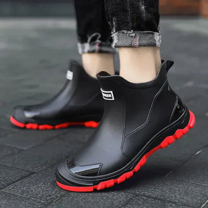 Men's waterproof black ankle boots with red outsole, side panels, and pull tabs