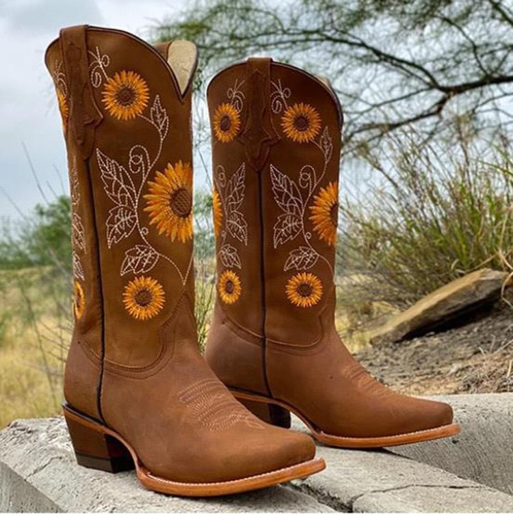 Brown cowboy boots with sunflower embroidery and tan stitching, outdoor side view