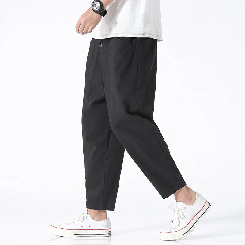 Black cropped drawstring pants with elastic waistband, relaxed tapered legs
