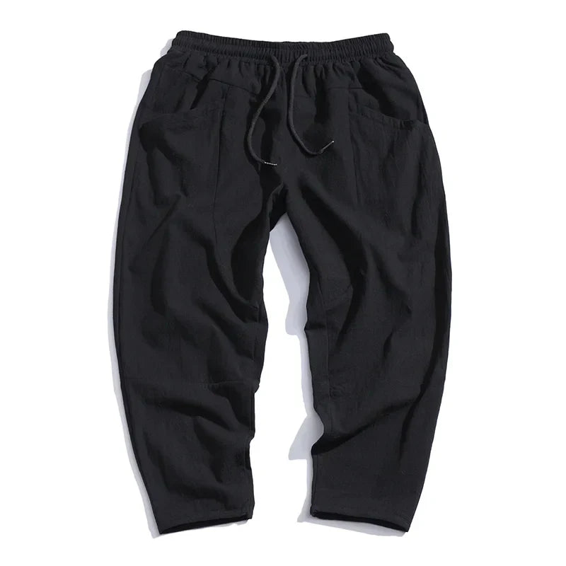 Black cropped drawstring pants with elastic waistband, relaxed tapered legs