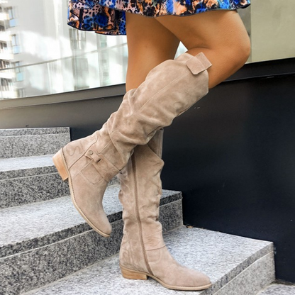 Beige knee-high flat boots with buckle strap and seam detail