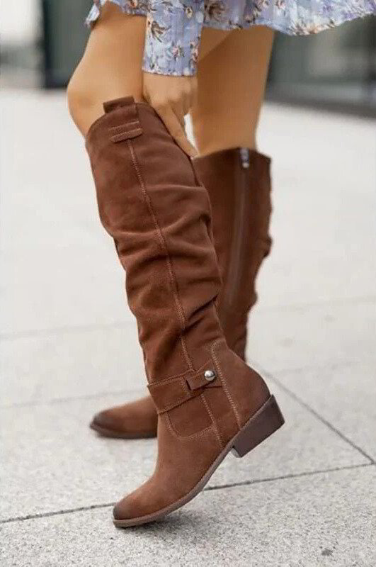 Brown knee-high flat boots with side buckle strap and stitched panels