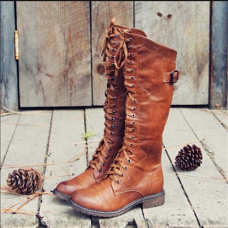 Brown high lace-up riding boots with buckle strap and stitched seams.