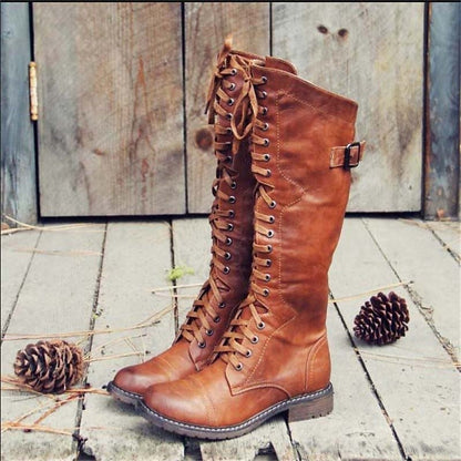 Brown high lace-up riding boots with buckle strap and stitched seams.
