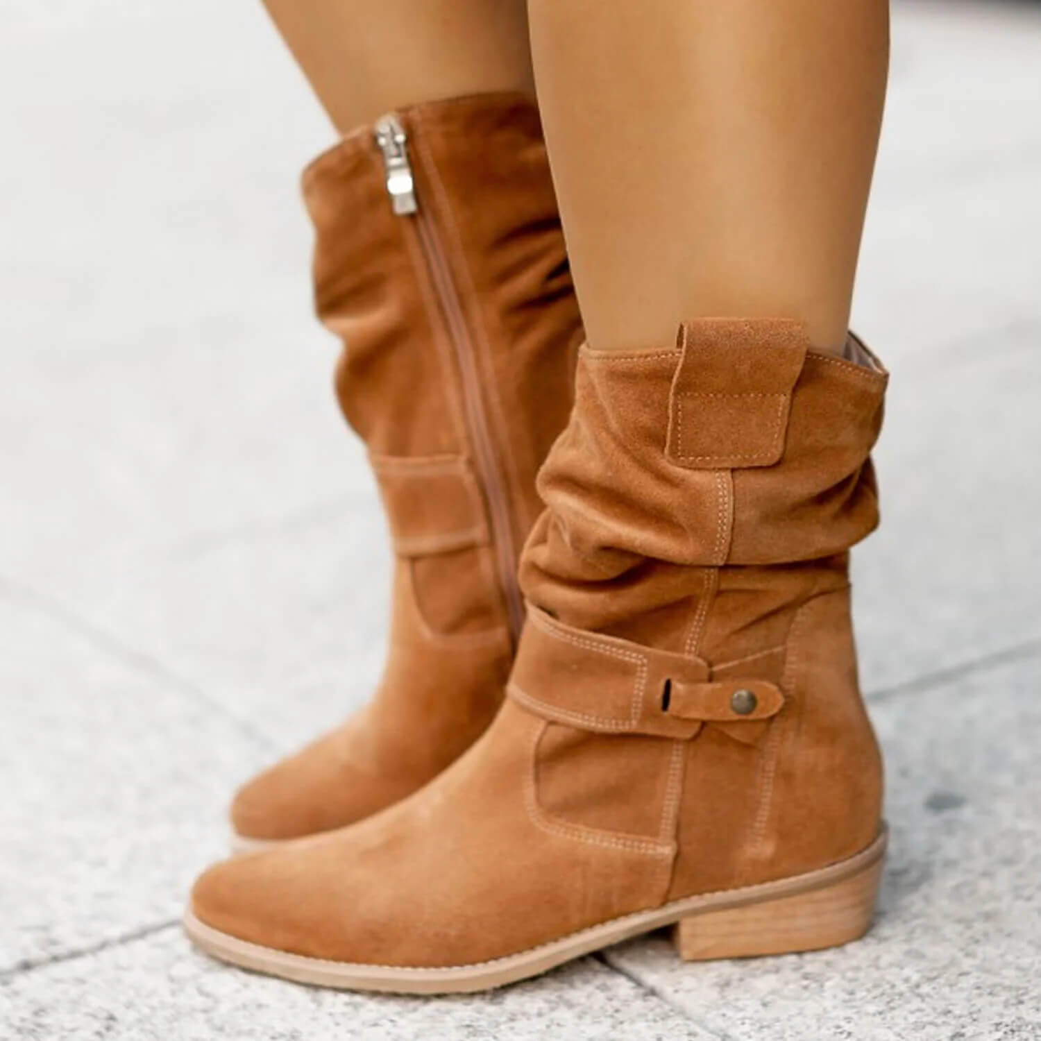 Tan suede slouch boots with front buckle strap, side zipper, and stacked heel