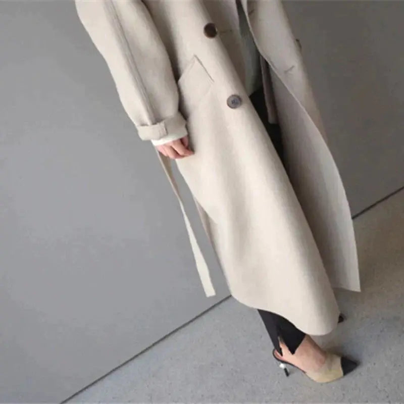 Beige long wool coat with belted waist, button front, and long sleeves with cuffs