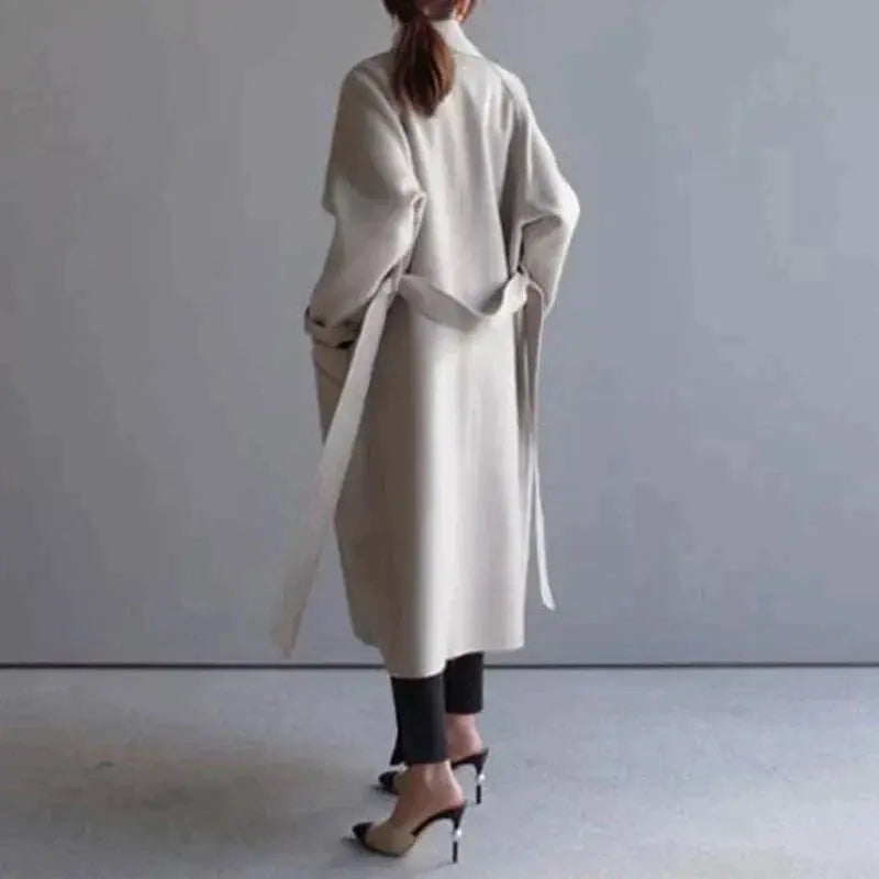 Beige long wool coat with wrap-style neckline, belt, and midi length silhouette