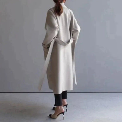 Beige long wool coat with wrap-style neckline, belt, and midi length silhouette