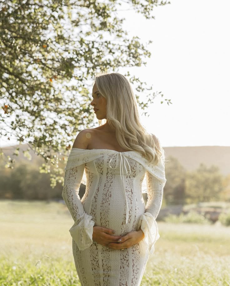 White off-shoulder lace maternity dress with long sleeves and fitted waist, side view