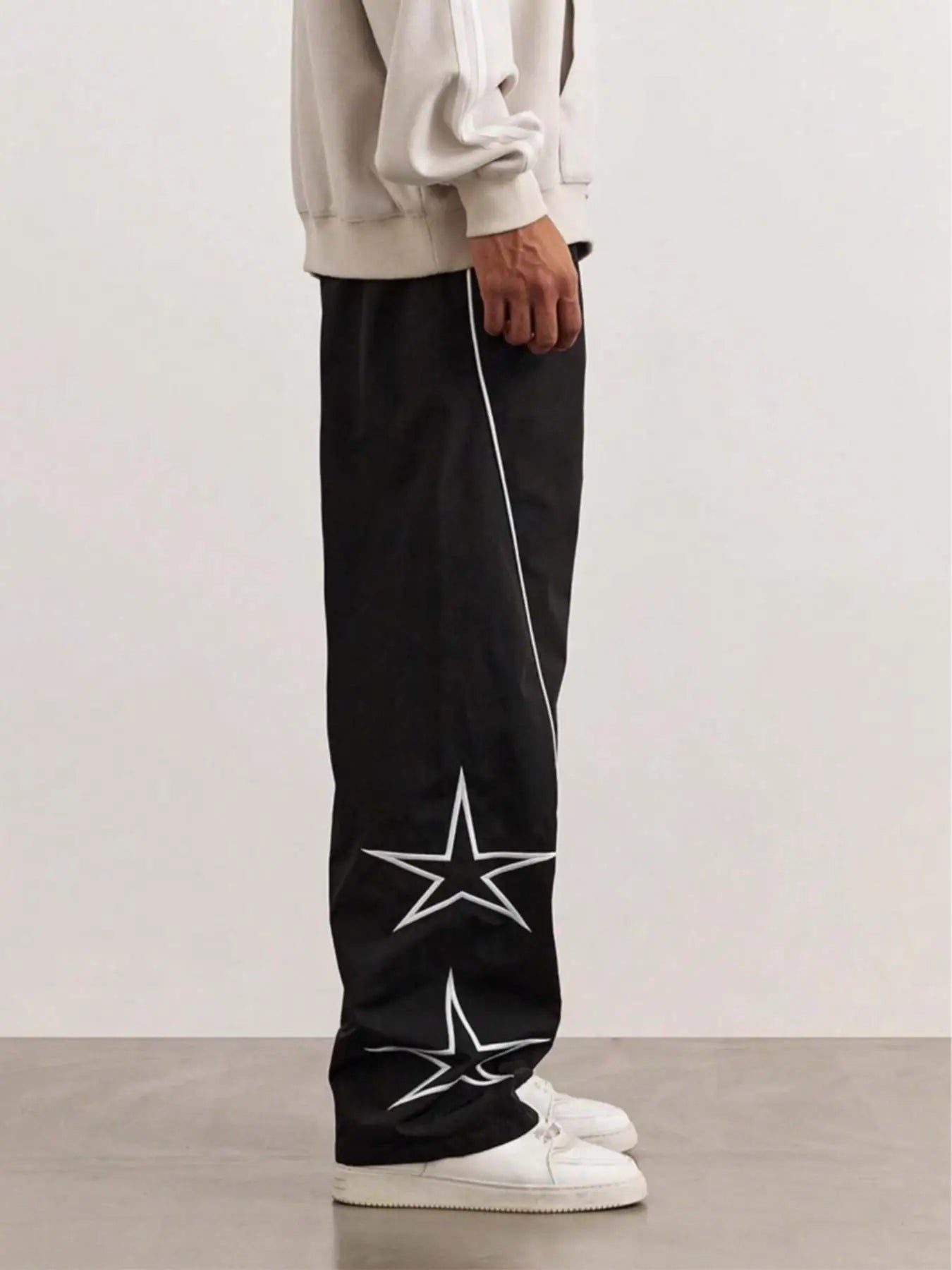 Black quick-dry trousers with white side stripe and star graphic, relaxed straight legs.