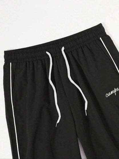 Black quick-dry trousers close-up: elastic waist, drawstring ties, white side stripes.