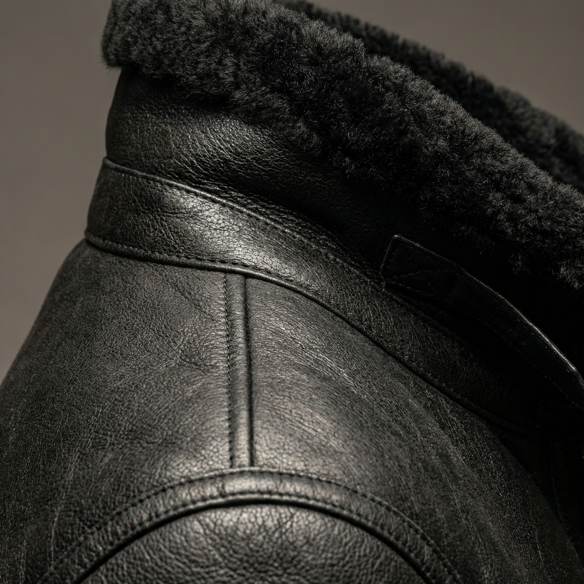 Black leather aviator jacket shoulder close-up with shearling trim and seam stitching