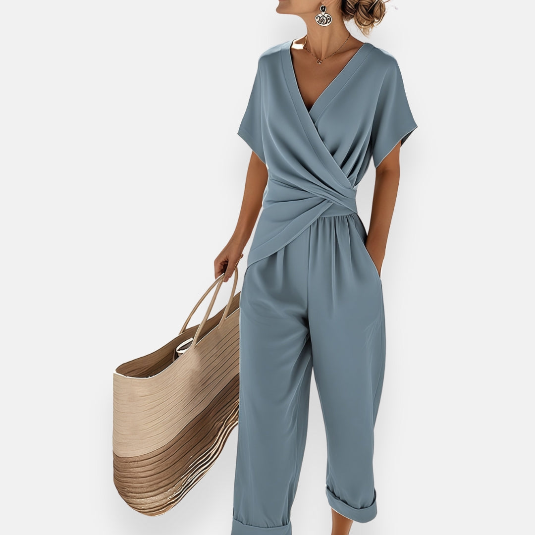 Blue wrap-style jumpsuit with V-neck, short sleeves, tied waist, wide cropped legs