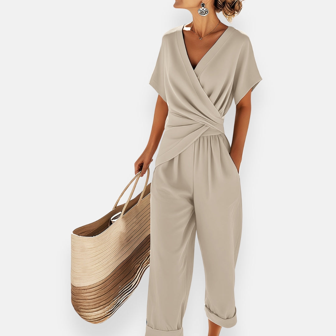 Beige wrap-style jumpsuit with V-neck, short sleeves, draped waist, wide cropped legs