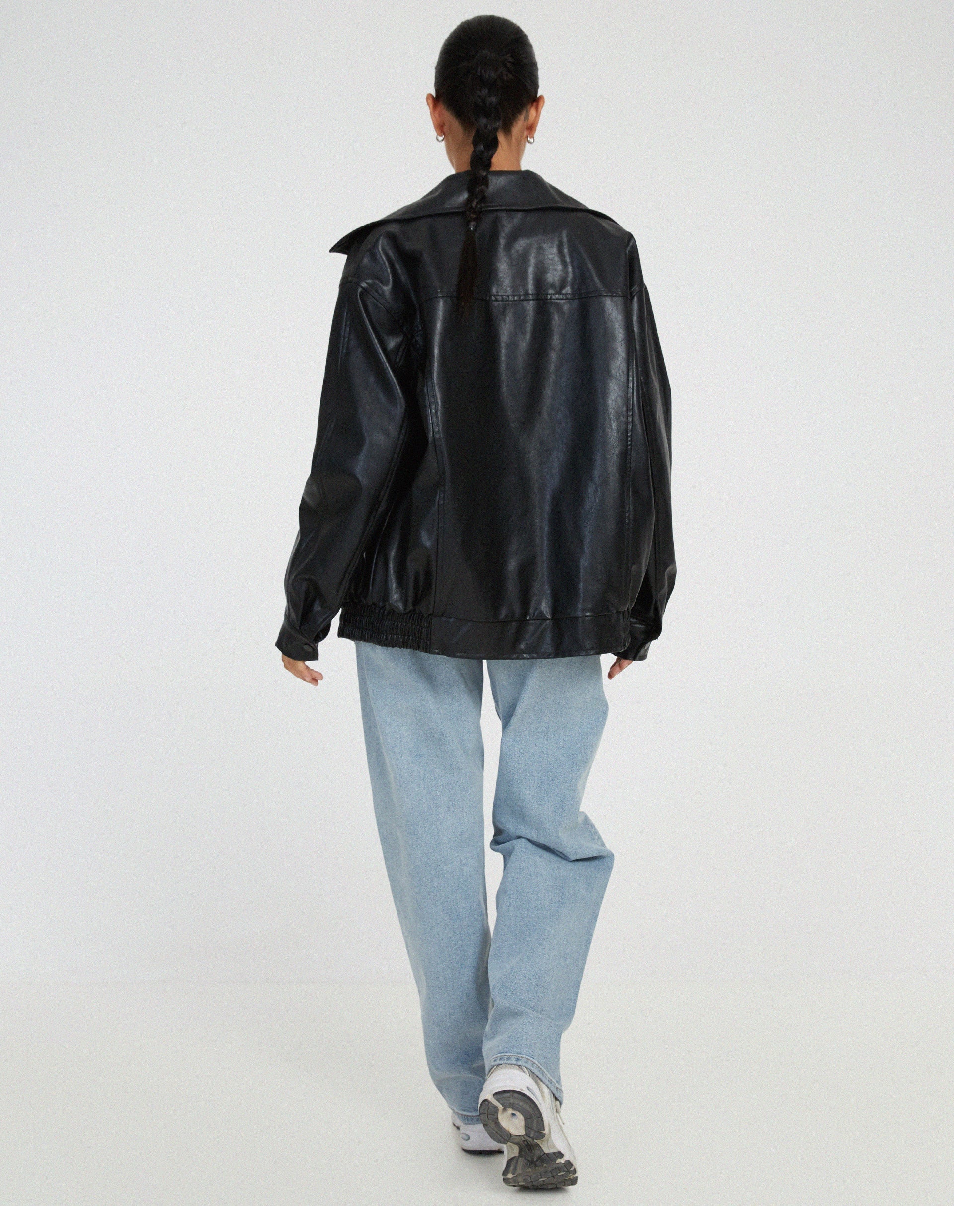 Black oversized PU leather jacket back view with full-length zip and elastic hem.
