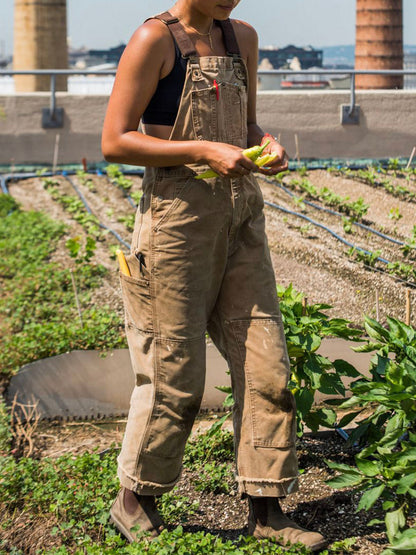 Men's tan canvas bib overalls with adjustable straps and multiple utility pockets