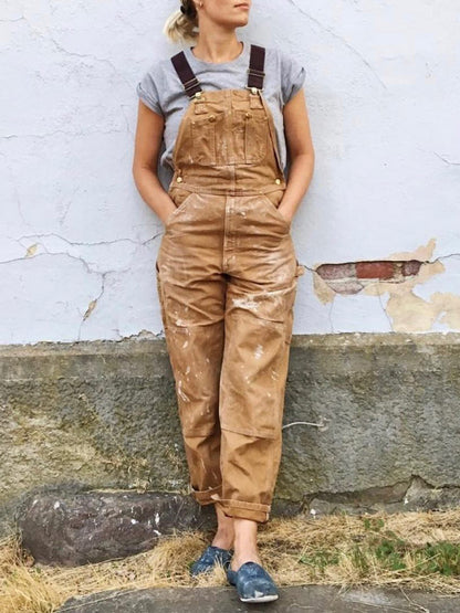 Men's tan canvas bib overalls with adjustable straps and front utility pockets