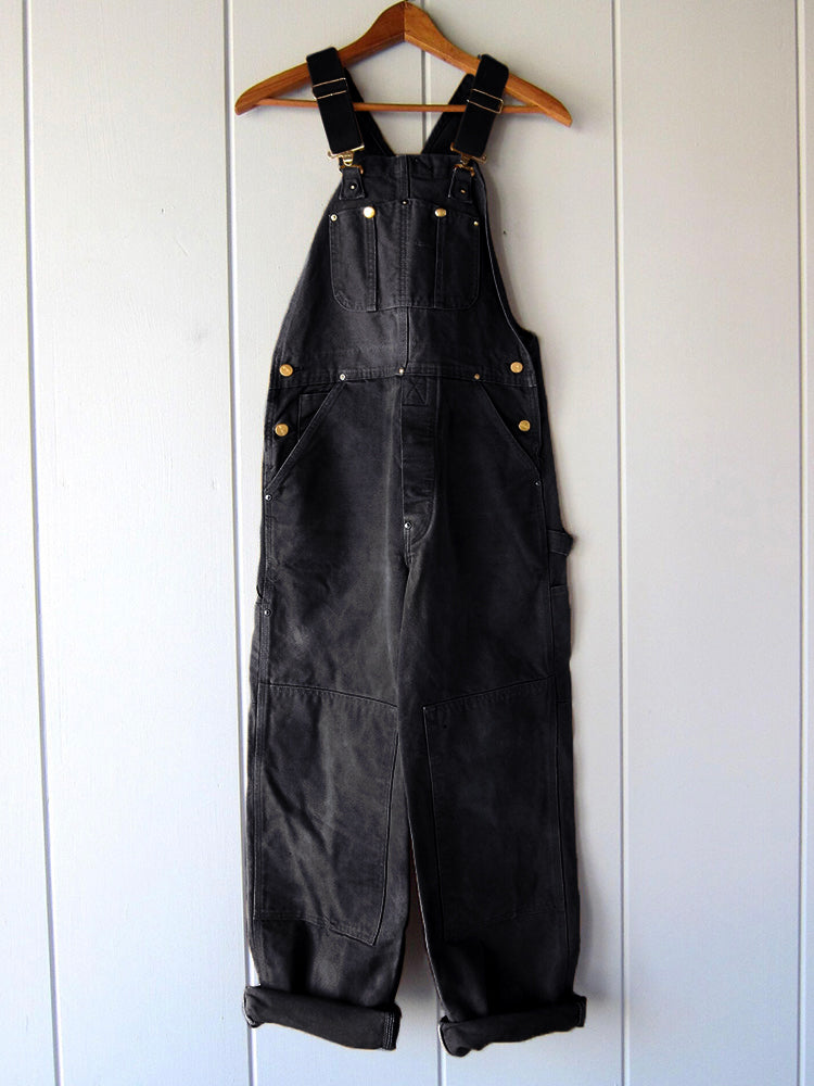 Men's black canvas bib overalls with adjustable straps and front utility pockets