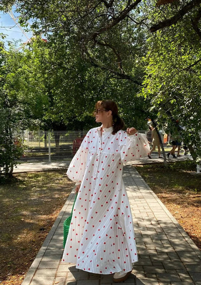White maxi dress with red heart print, long sleeves, button front, full skirt