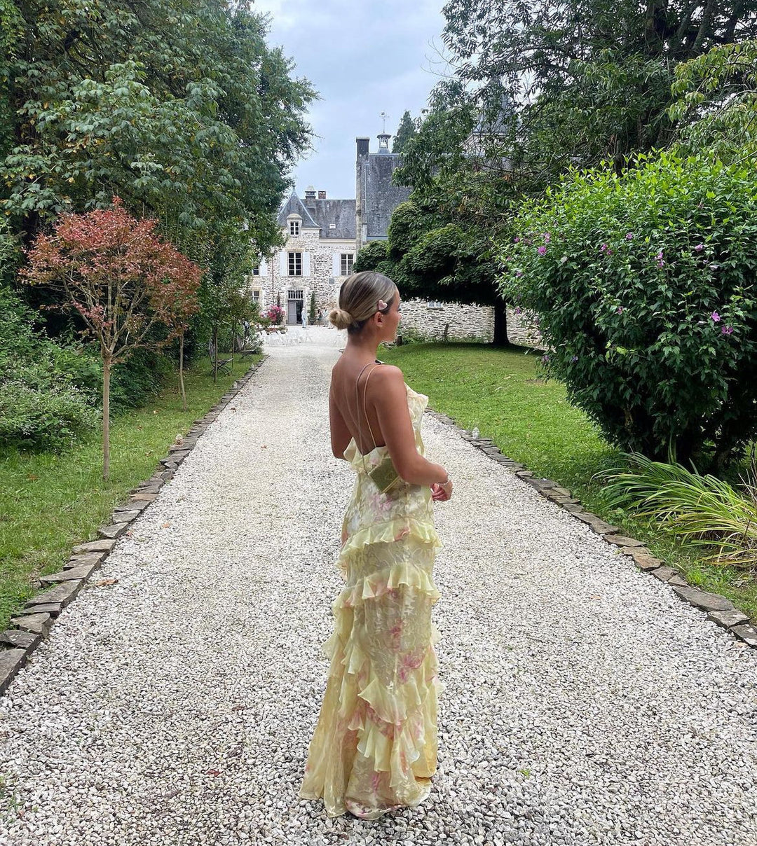 Ruffled tiered maxi dress with spaghetti straps, pastel floral print, outdoor side view