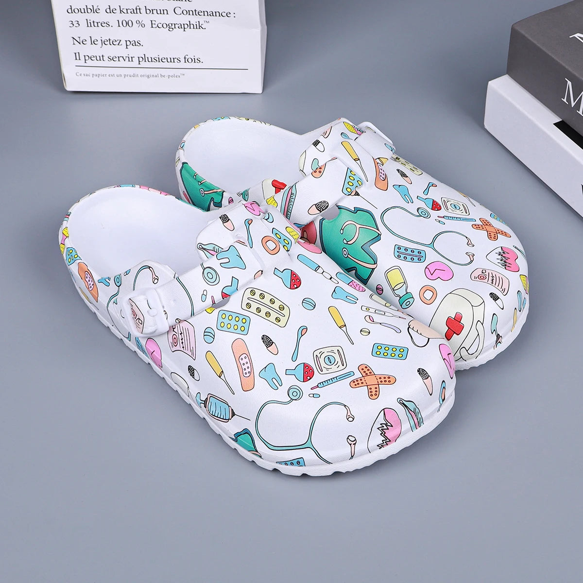 White medical-print nurse clogs, open mule design with adjustable buckle straps.
