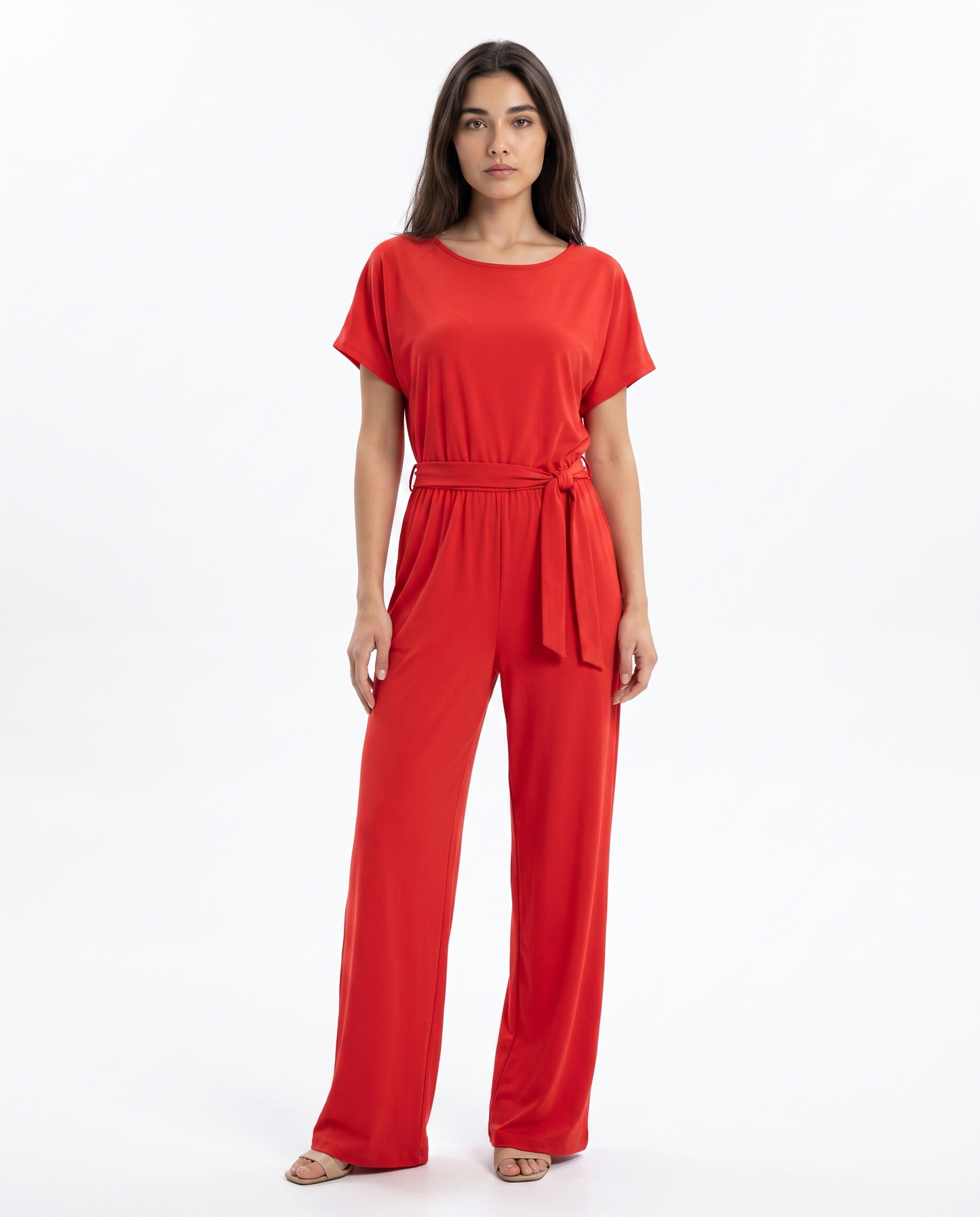 Women's red jumpsuit with tie waist belt and wide legs, worn with flat sandals