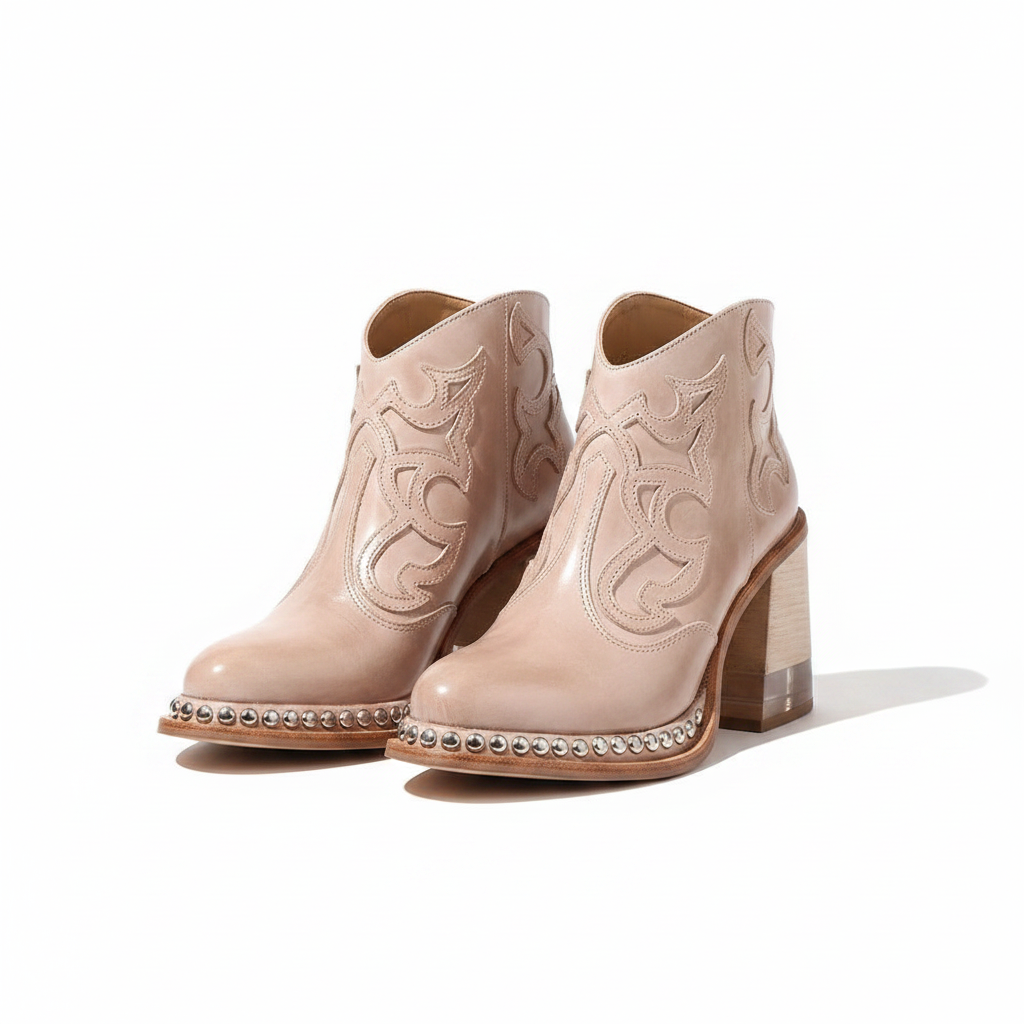 Pair of women's western ankle boots in blush pink with ornate stitching and silver-stud trim