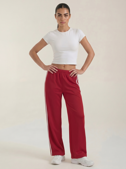 Red wide-leg track pants with elastic waistband, drawstring tie, and white side stripes