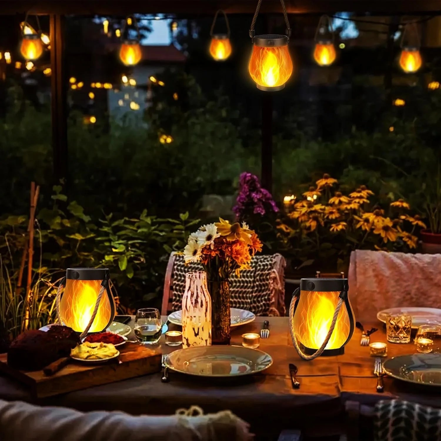 Lit solar flame lanterns with rope handles and black tops for garden decor